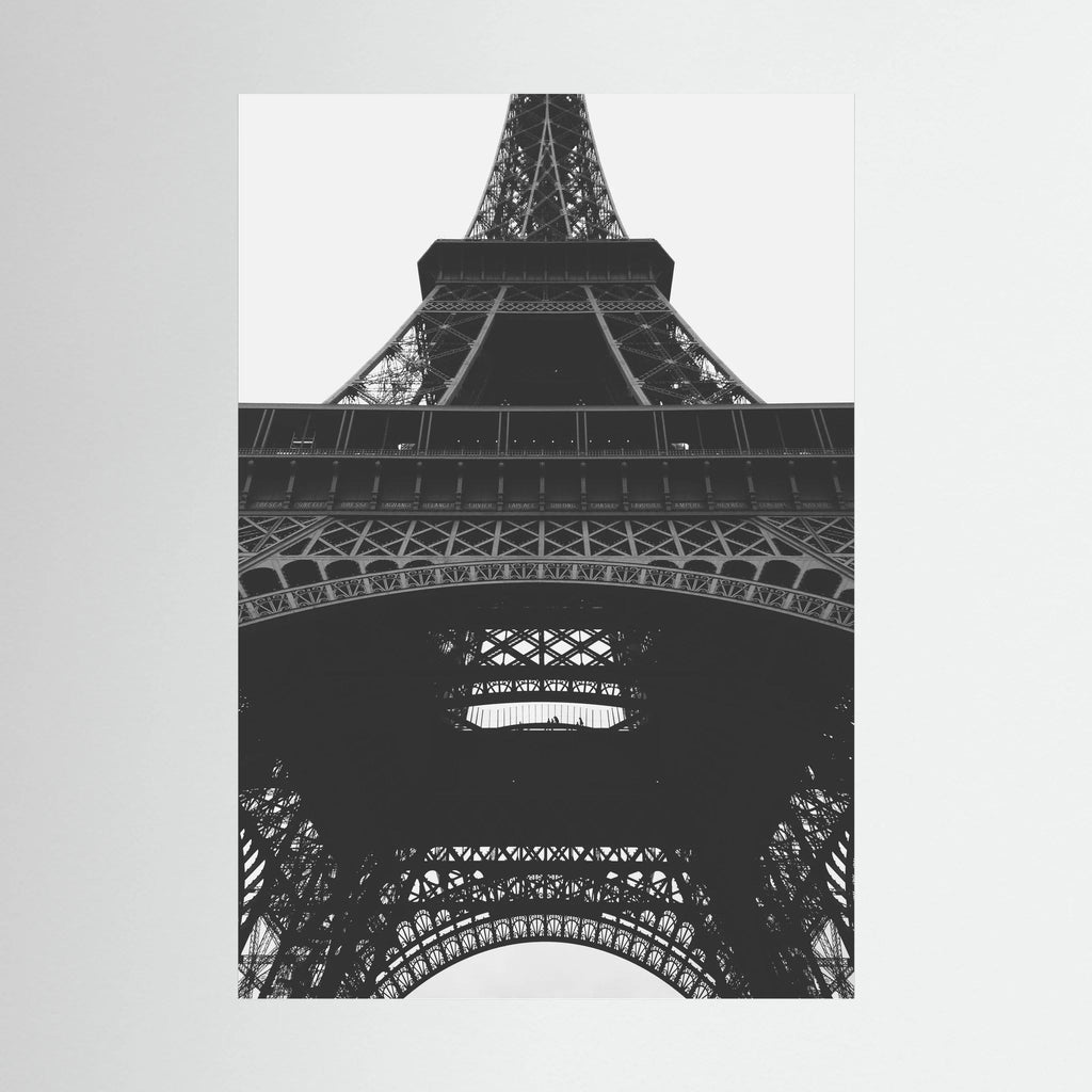 Black and white view looking upward through the iron structure of the Eiffel Tower.