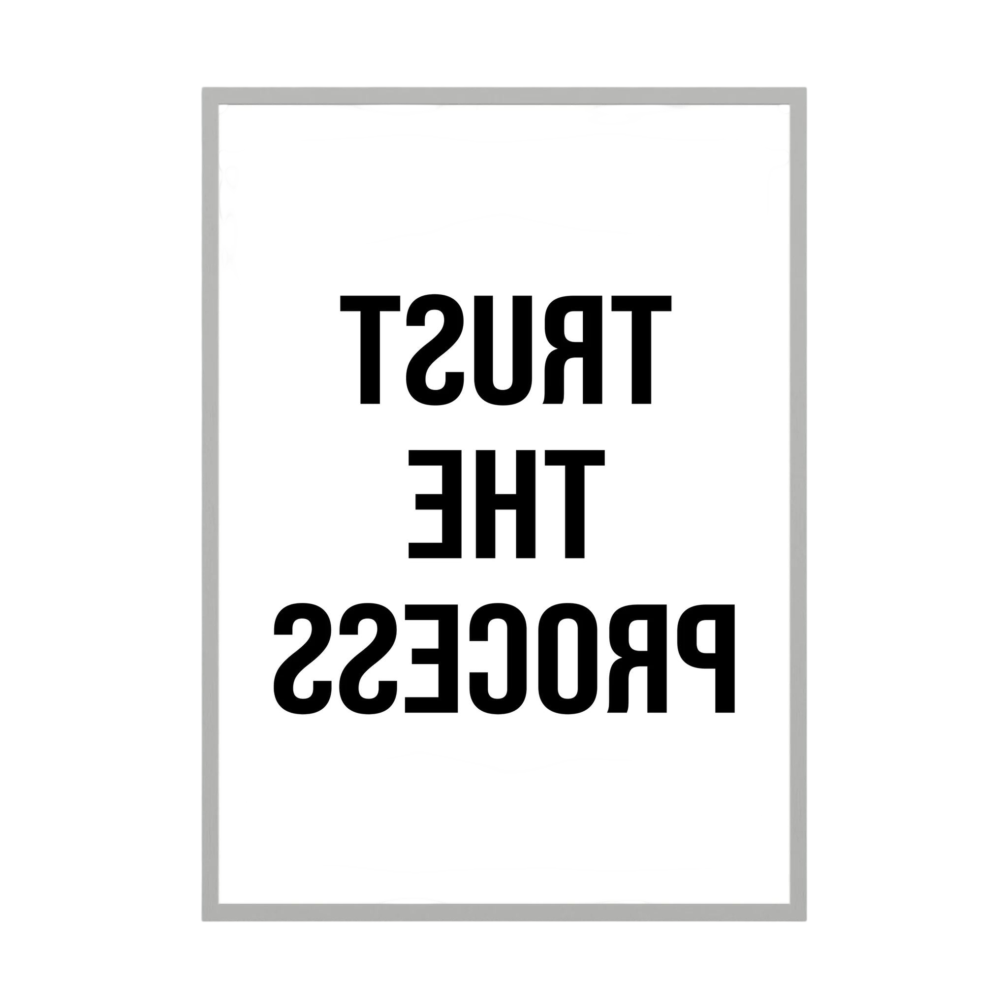 Black mirrored typography spells trust the process backwards against a clean white background.