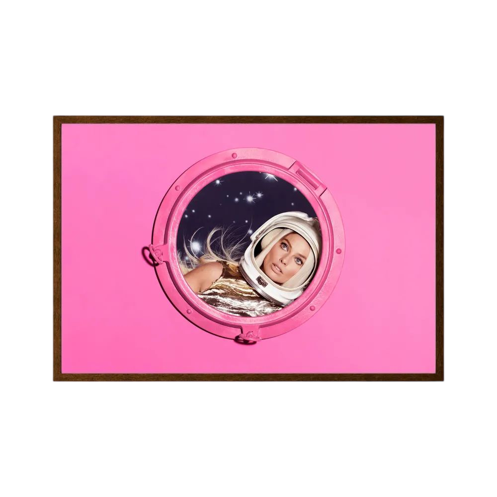 Woman in a metallic astronaut suit looks through a circular porthole set in a vivid pink field.